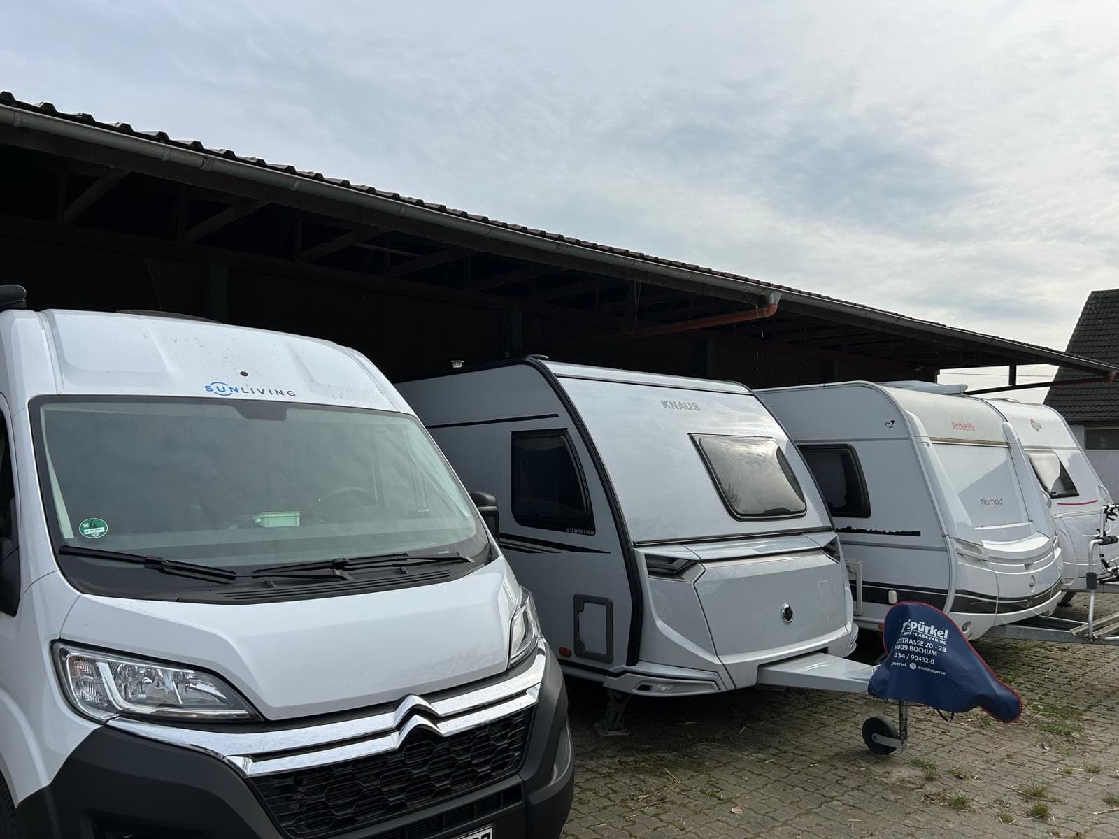 Wohnmobil und Wohnwagen auf den Camperstellplätzen unter einem Vordach.