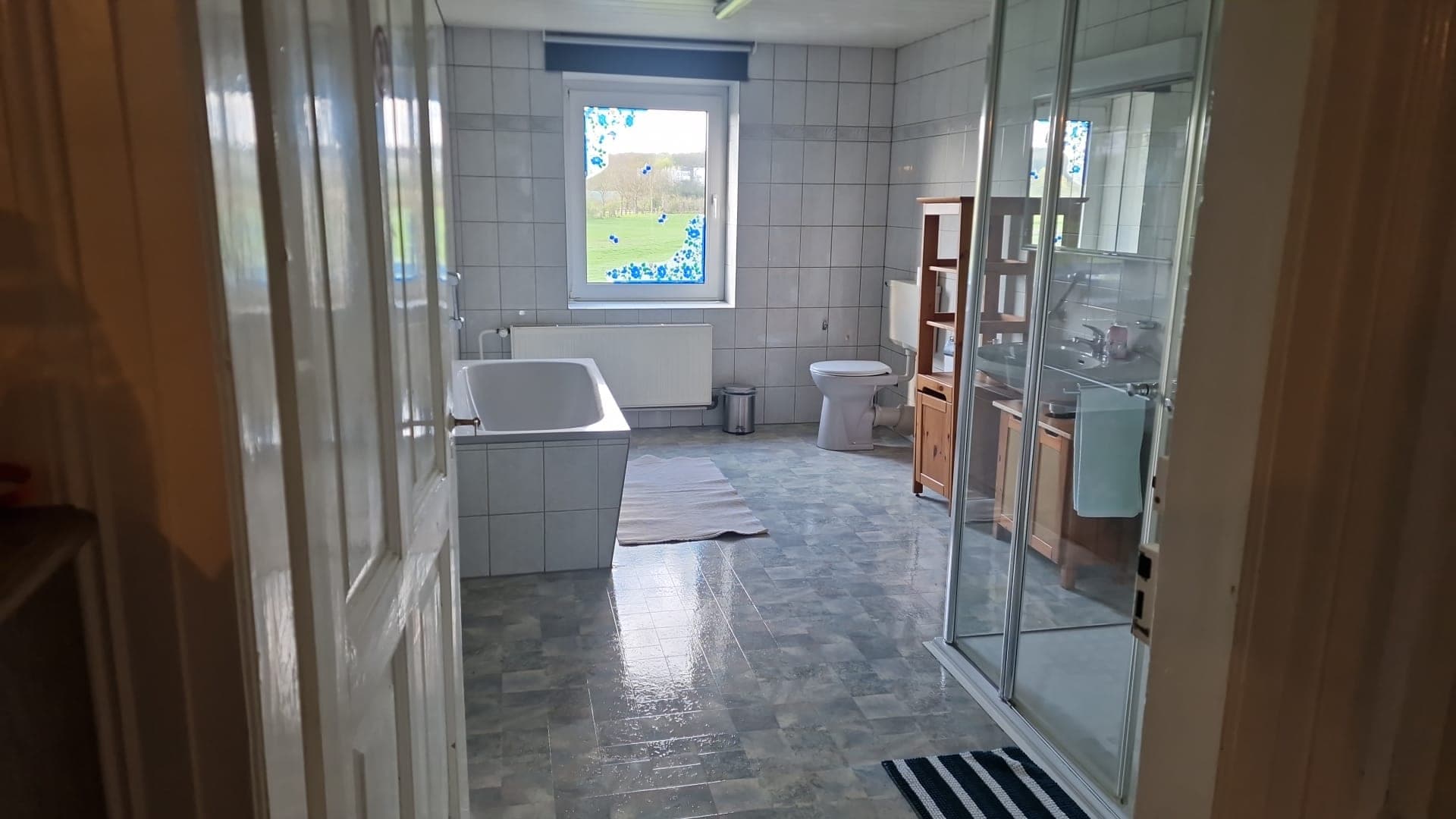 Badezimmer mit Badewanne, Duschkabine und Fliesenboden.