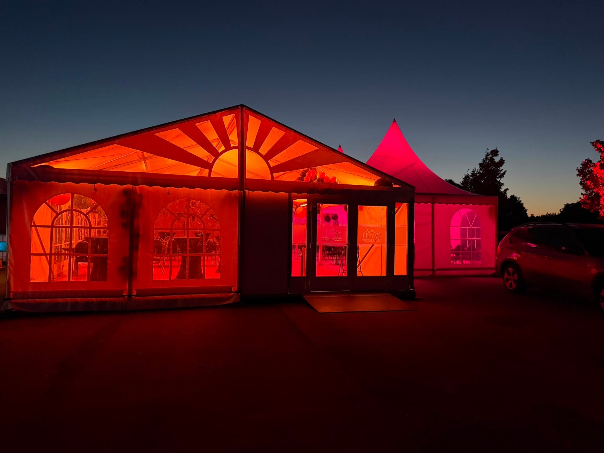 Rot beleuchtetes Festzelt in der Abenddämmerung.